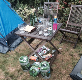 Kampeertafel met bier en flesjes naast de tent